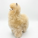 A fluffy alpaca plush toy with cream and light tan fur, standing against a seamless white studio background.