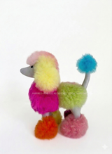 A curated collection of vibrant, multi-color artisan alpaca fur plush toys, including a rainbow poodle, pastel lion, and stuffed teddy bear on a clean neutral backdrop. An editorial text overlay highlights unique, handmade heritage gifts from Peru