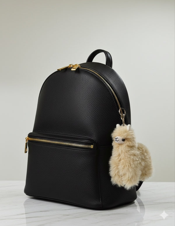 Beige Lucky Llama alpaca fur bag charm clipped to a black backpack