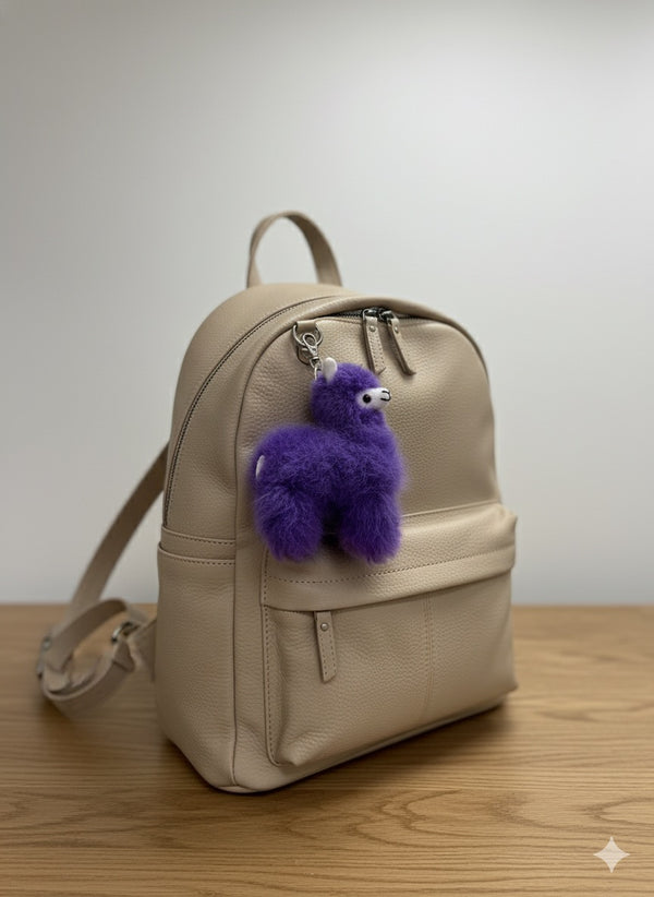 Lavender Lucky Llama alpaca fur bag charm on a beige backpack