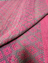 Detail of Frazada No. 113 showing dense two-tone diamond eye weave pattern in fuchsia and warm grey with traditional central union seam and distinctive teal whipstitch perimeter edge