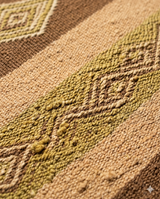 Macro texture view of hand-spun Andean wool with natural slubs and high-tension weave, demonstrating the tactile grit and weight of a traditional Peruvian floor textile.