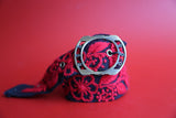 Hand-woven red and black wool belt with vibrant floral embroidery.